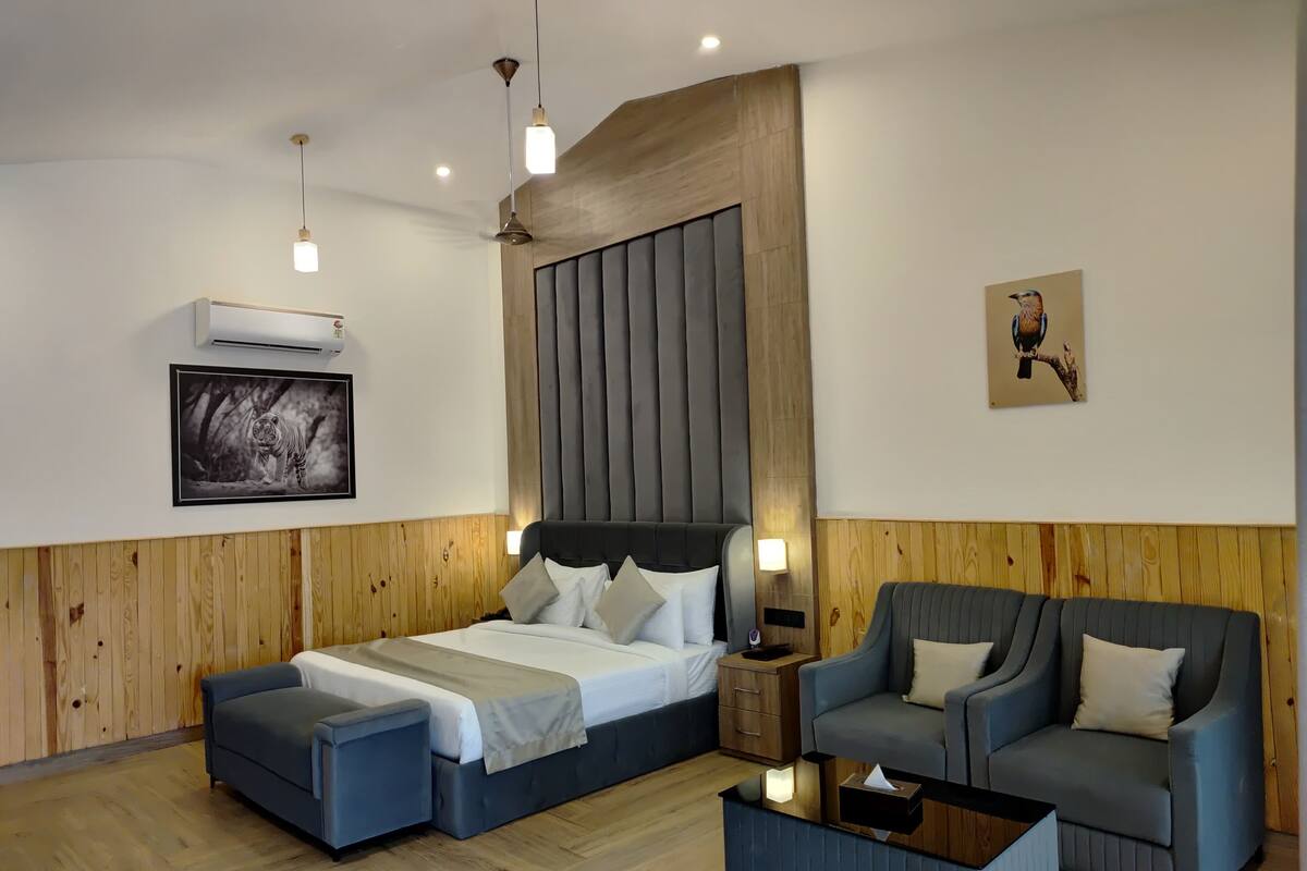 A modern hotel room with a large bed, a sofa, a coffee table, and a wooden accent wall.