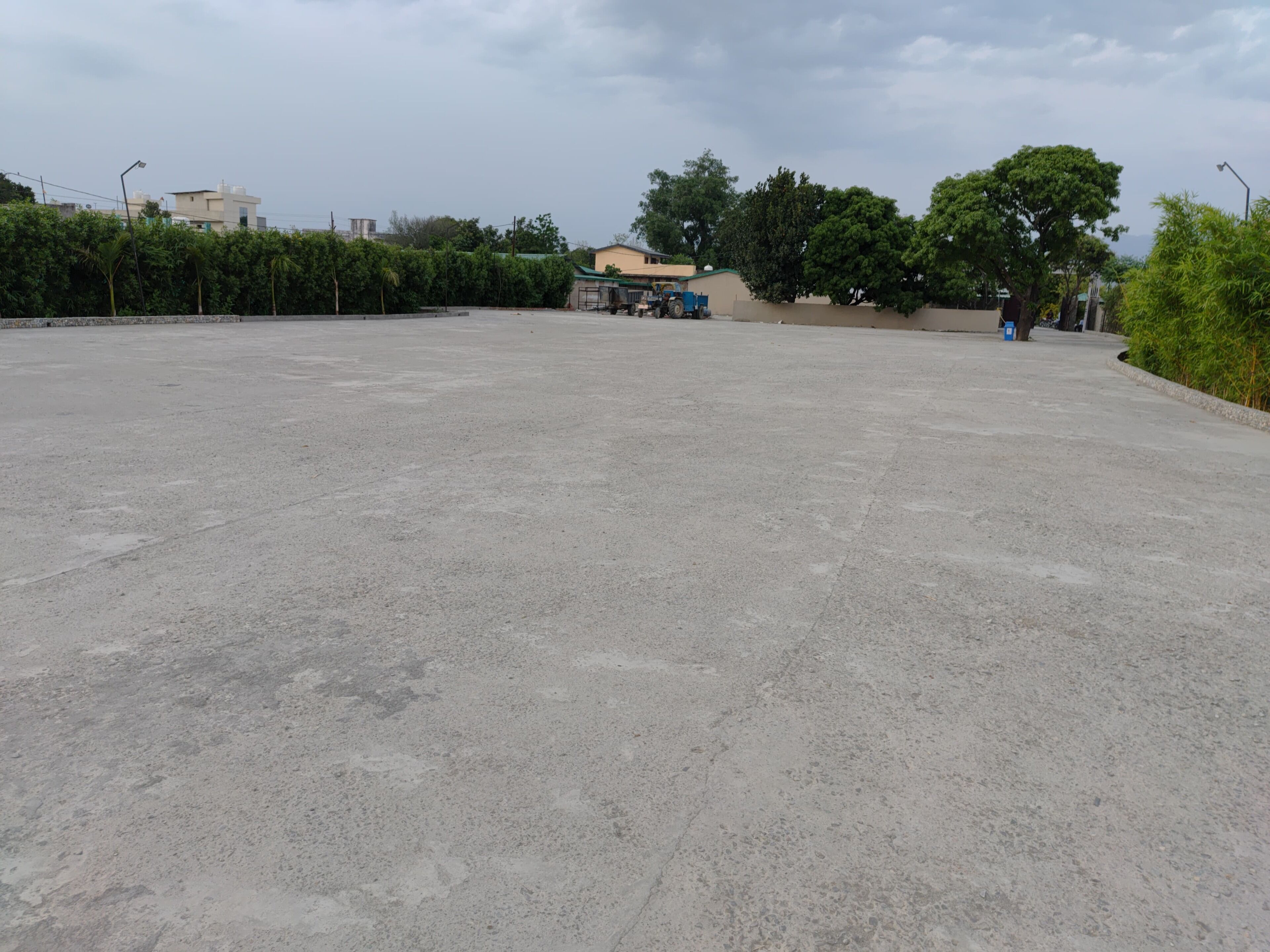 A spacious concrete area with a building in the background, surrounded by greenery.