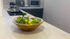 Une cuisine avec un saladier en bois contenant des feuilles vertes et une plante en pot posée sur le comptoir.