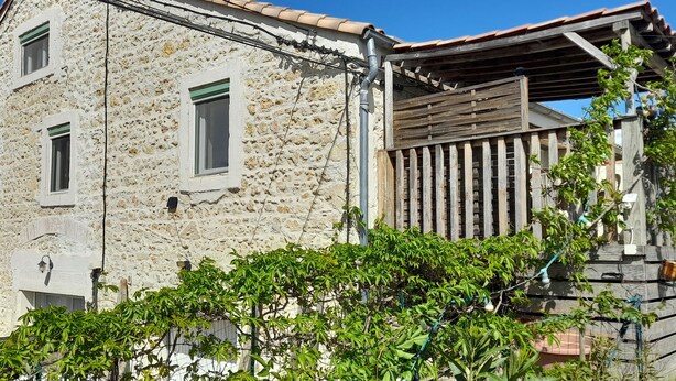 A stone building with a wooden balcony and a tiled roof.