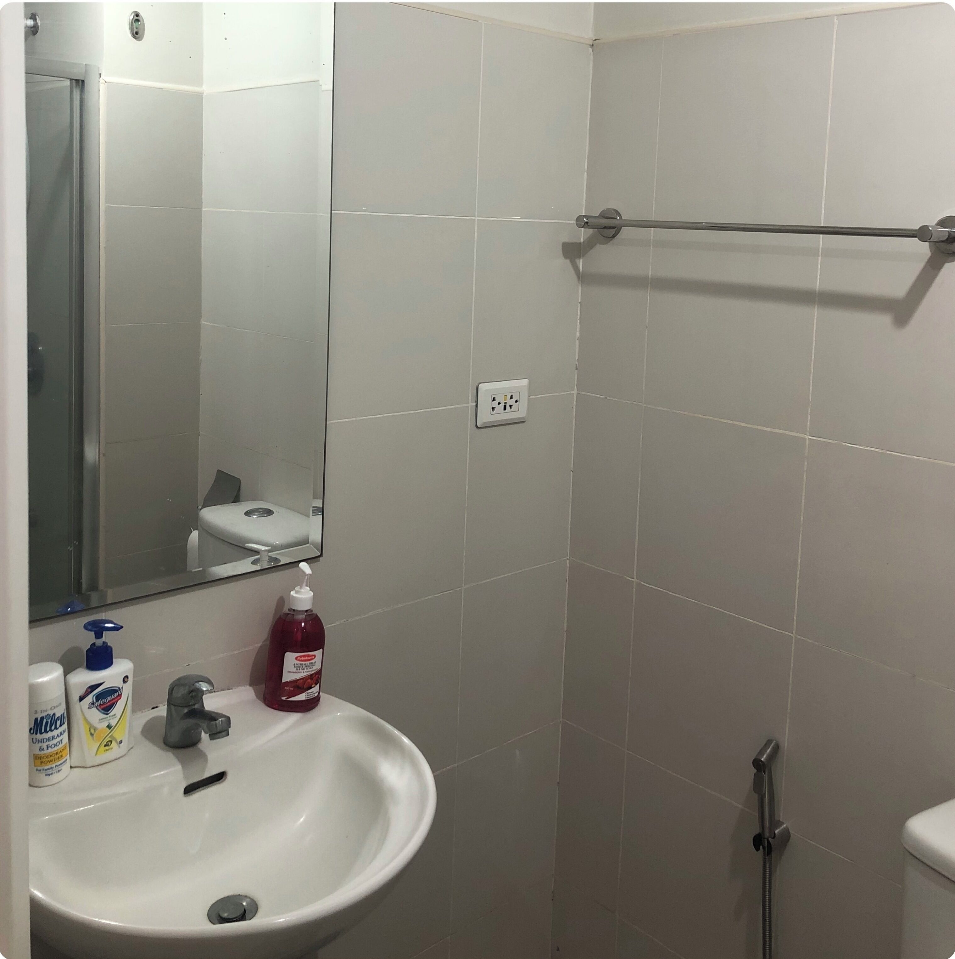 A bathroom with a white sink, mirror, and a shower area.