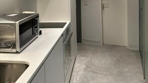 A modern kitchen with stainless steel appliances, a white countertop, and a tiled backsplash. - Suite No1 (Rethymno)