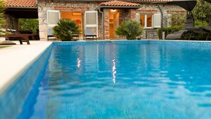 Una piscina con una casa de piedra al fondo.