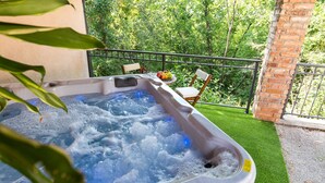 Un jacuzzi con una mesa y sillas, rodeado de follaje y un muro de ladrillo.