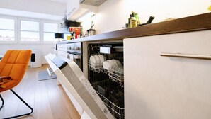A modern kitchen with a dishwasher, a wooden countertop, and a window overlooking a cityscape.