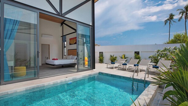 A modern pool area with glass doors leading to a bedroom, lounge chairs, and a clear blue sky. - New 17m Eco Pool Villa Sunset Garden 12 (Rawai)