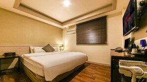 A hotel room with a bed, a desk with a telephone, a hairdryer, and a television mounted on the wall. - HOTEL JUNO (Incheon)