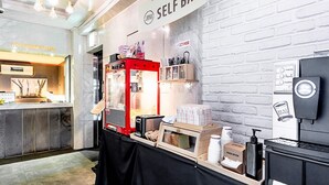 A self-service kiosk with a red machine, a paper dispenser, and a small display with various items. - HOTEL JUNO (Incheon)