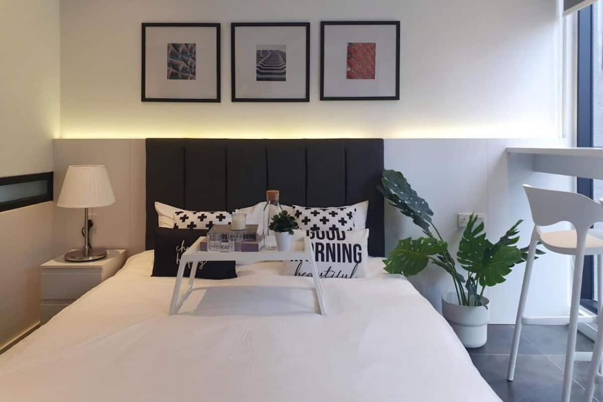 Une chambre d’hôtel moderne, équipée d’un lit, d’une table de chevet, d’une lampe et offrant une vue sur l’extérieur.