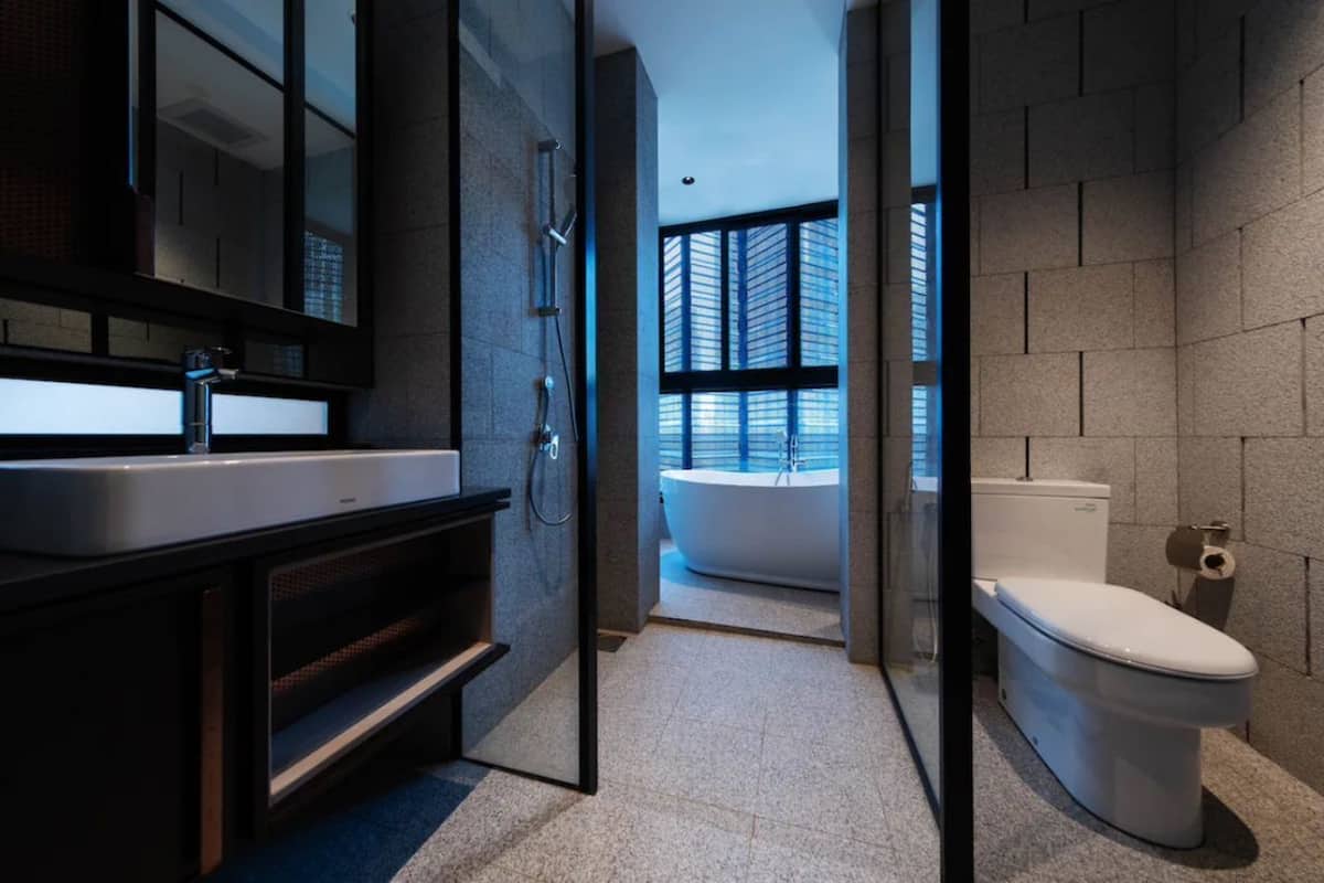 Une salle de bain moderne avec un grand miroir, une baignoire et des toilettes.