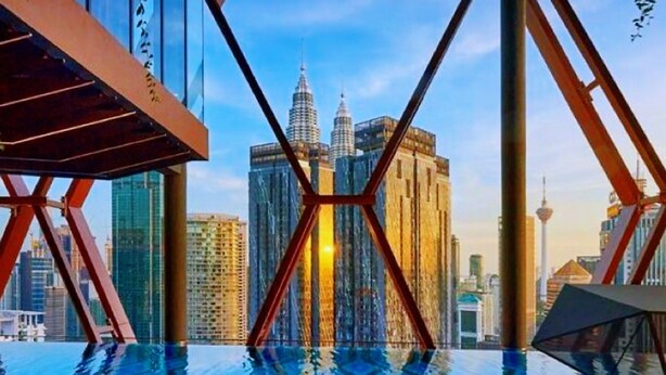 A rooftop infinity pool with a view of the Petronas Towers and a tower in the background. - Scarletz Suites KLCC by Purple Orchid (Kuala Lumpur)