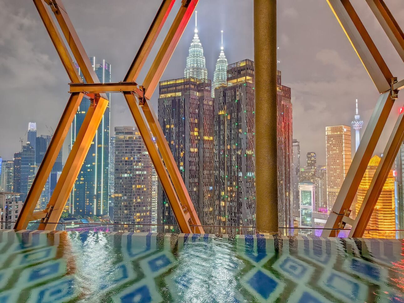 A view from a high-rise building with a glass floor, overlooking a cityscape with illuminated skyscrapers.