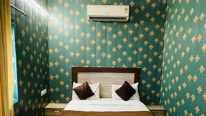 A hotel room with a large bed, a ceiling fan, and patterned wallpaper. - Hotel Taj Royale (Agra)