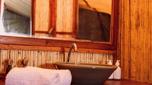A bathroom with a wooden vanity, a vessel sink, a towel, and a mirror. - Munga Plains (Kachikau)