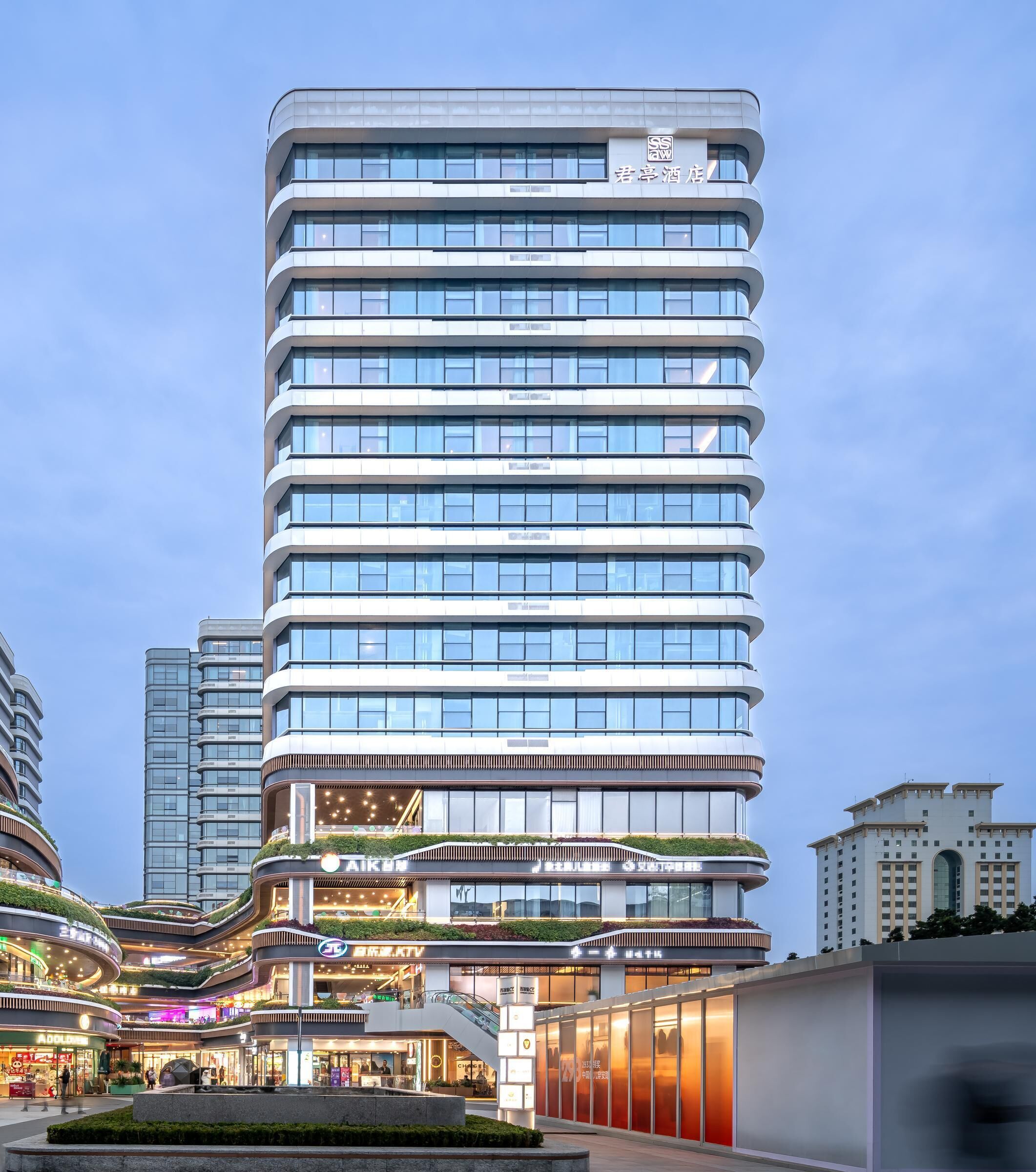 A modern hotel with multiple floors, a central atrium, and a rooftop garden.