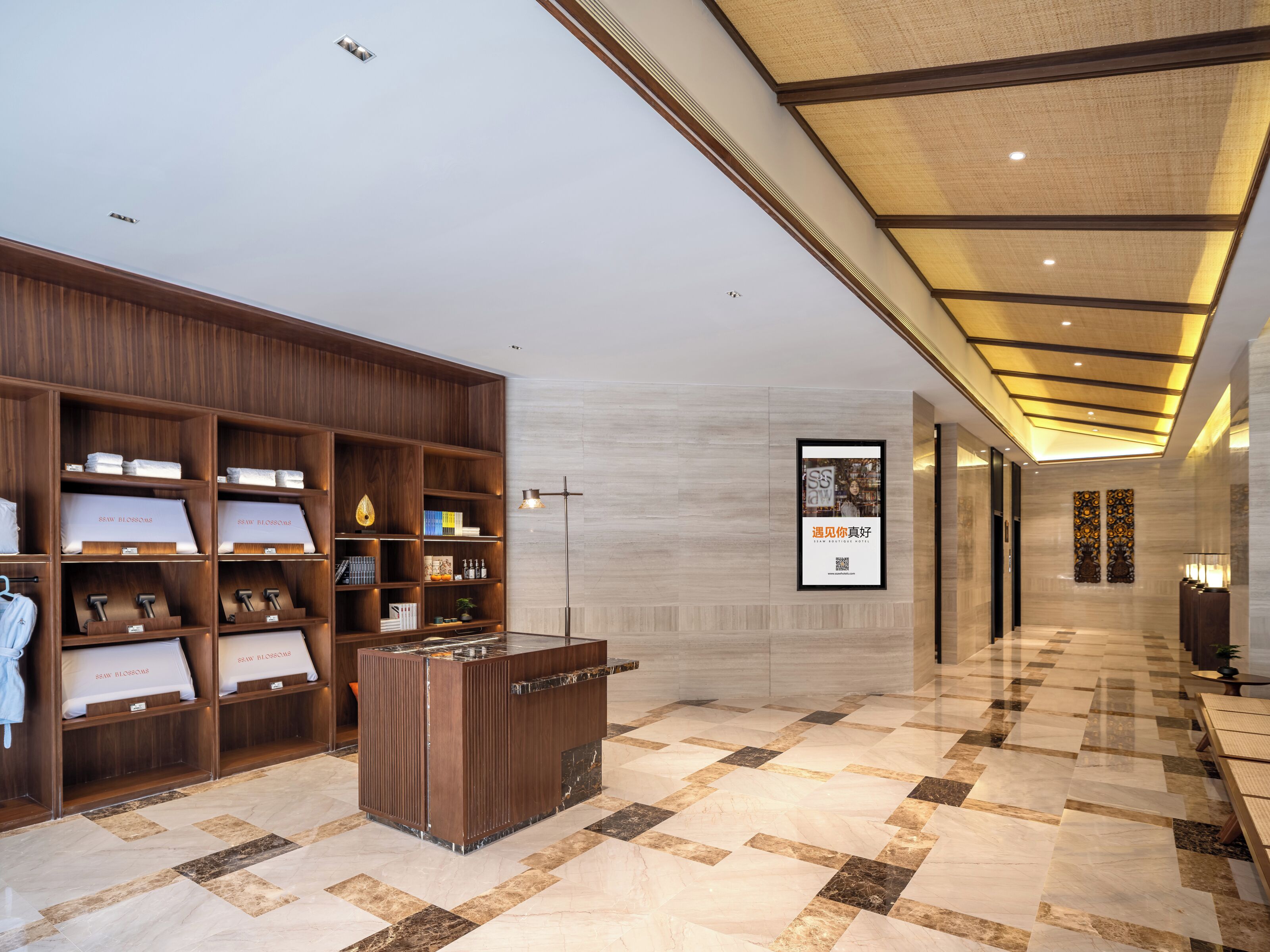 A hotel reception area with a wooden reception desk, a large framed poster on the wall, and a check-in counter.