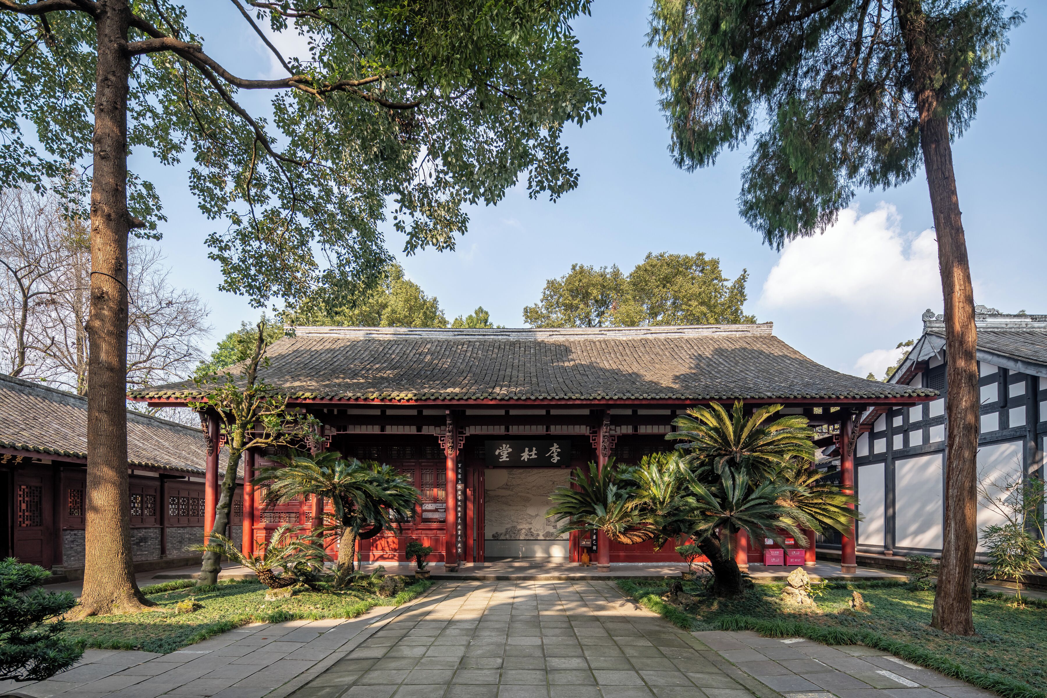A traditional building with a tiled roof, wooden pillars, and a stone pathway leading to the entrance.