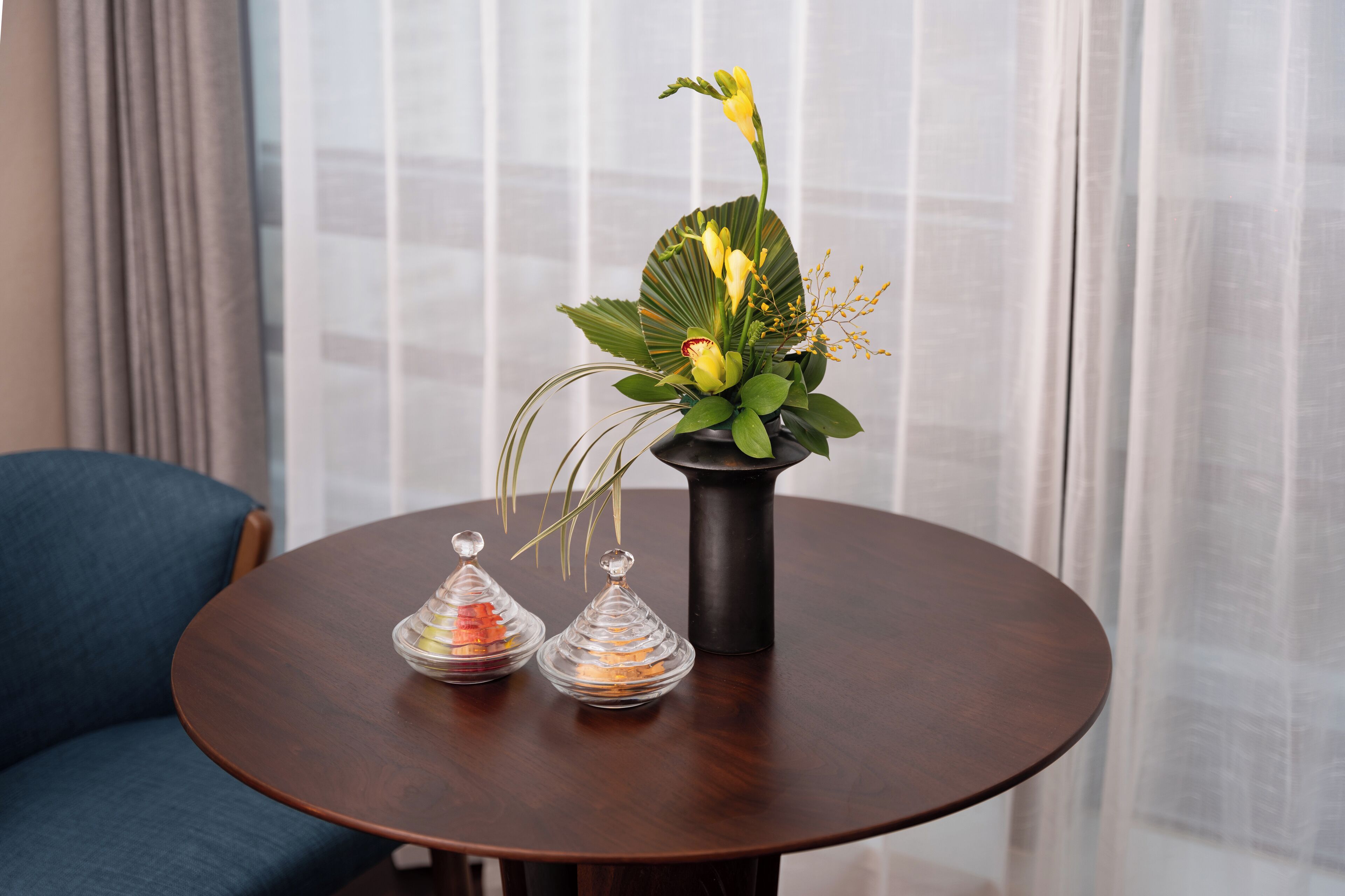 A round wooden table with a potted plant and two glass containers.