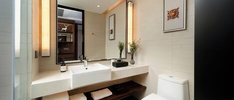 A modern bathroom with a large mirror, two sinks, a toilet, and a shelf with towels.
