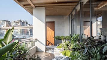 A modern balcony with a wooden slatted ceiling, a stone pathway, and lush greenery.
