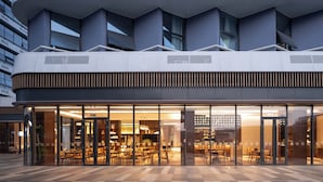 Un edificio moderno con fachada de vidrio, techo plano y varias ventanas.