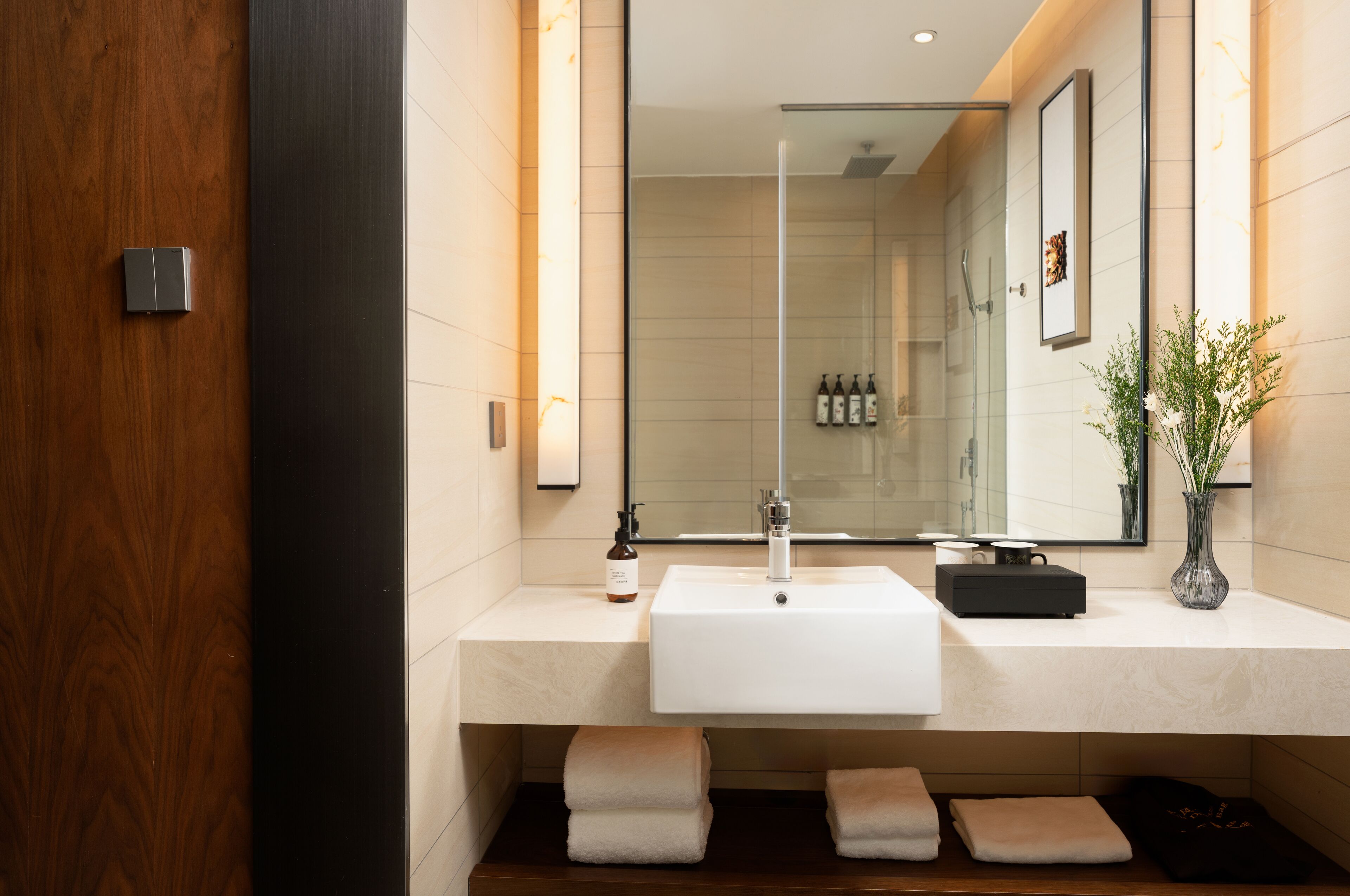 A modern bathroom with a white sink, a large mirror, and a glass shower enclosure.