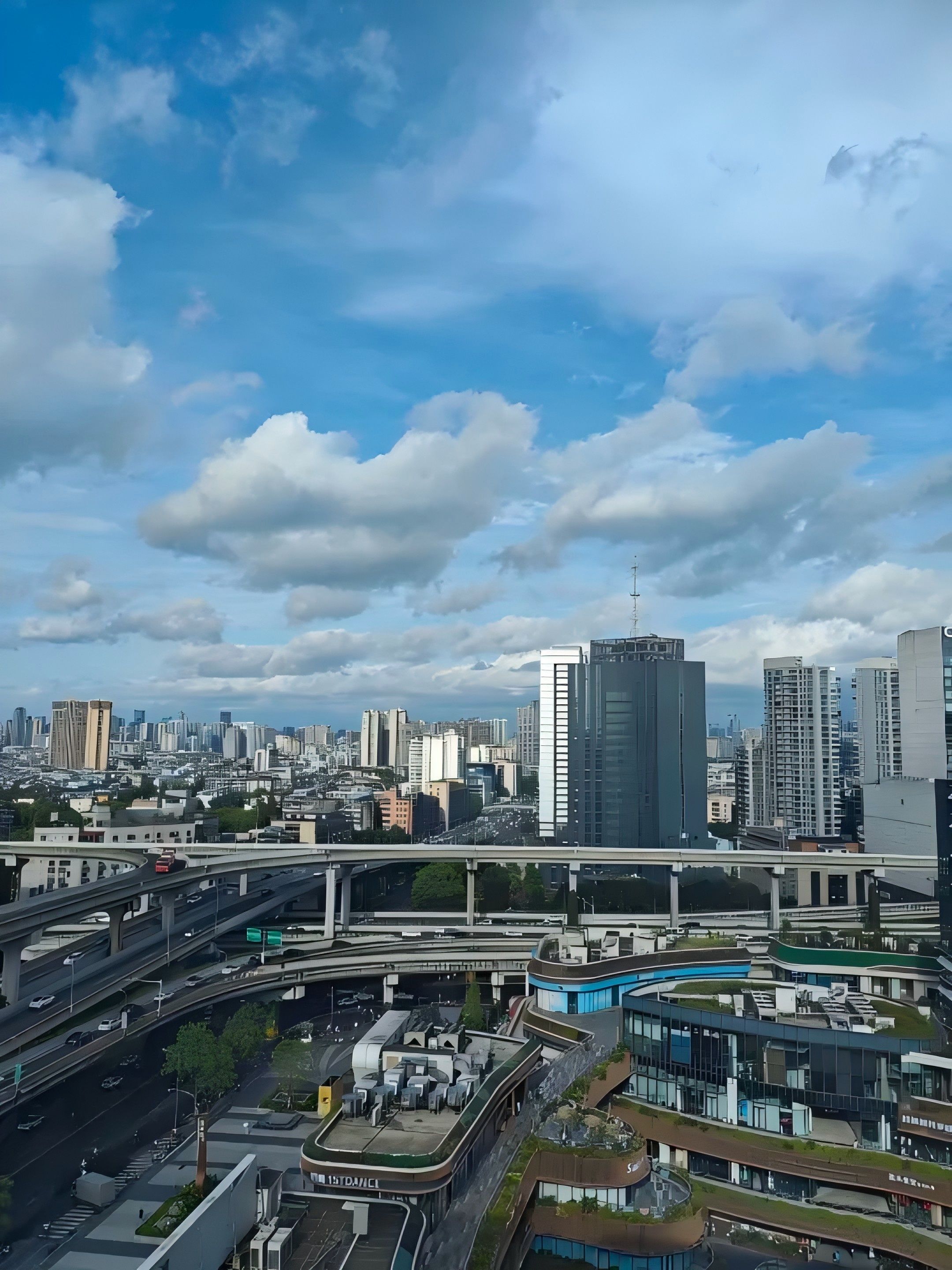 Un paysage urbain avec des bâtiments modernes, une autoroute et un ciel dégagé.