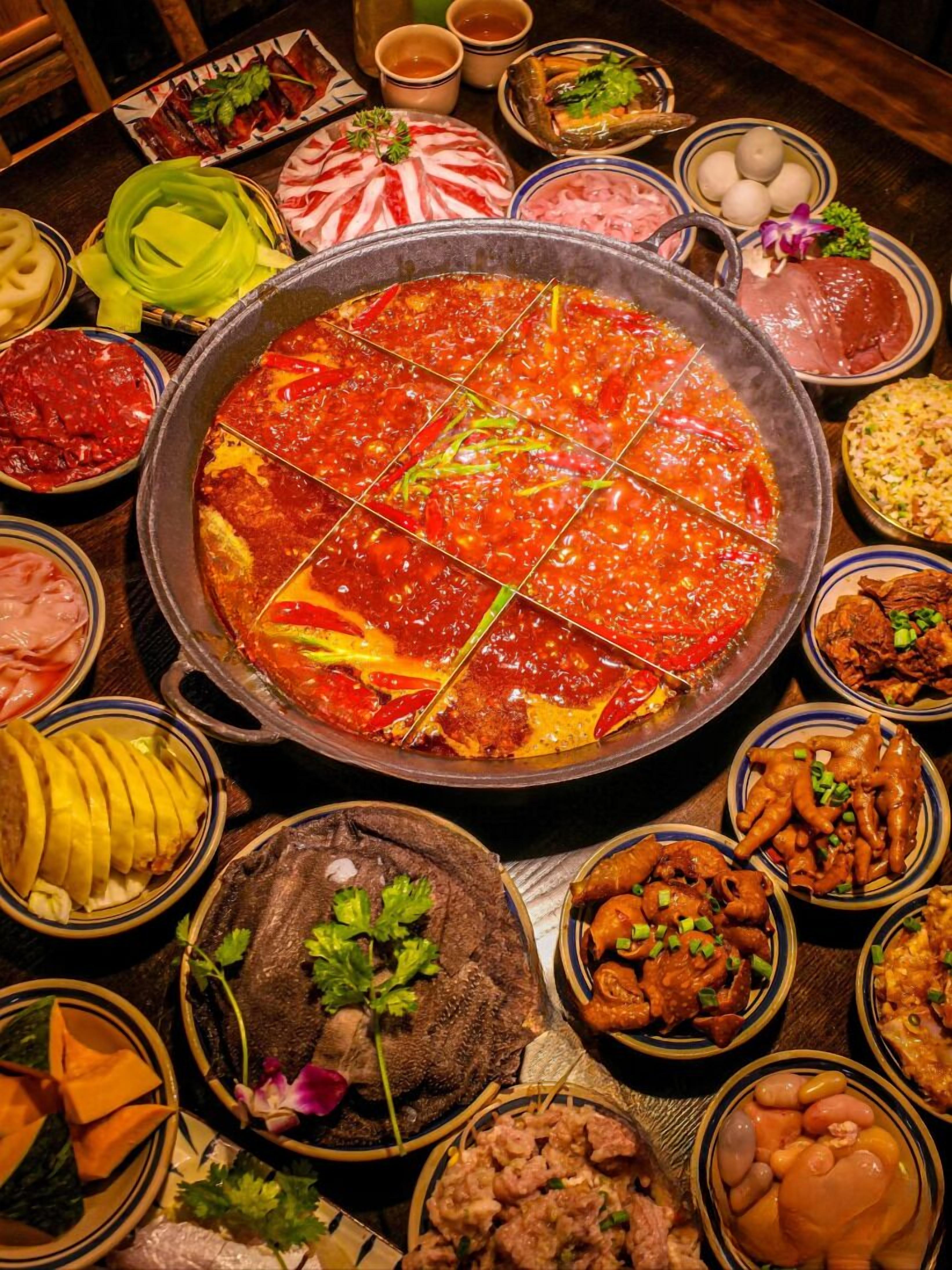 A variety of dishes arranged around a central hot pot.