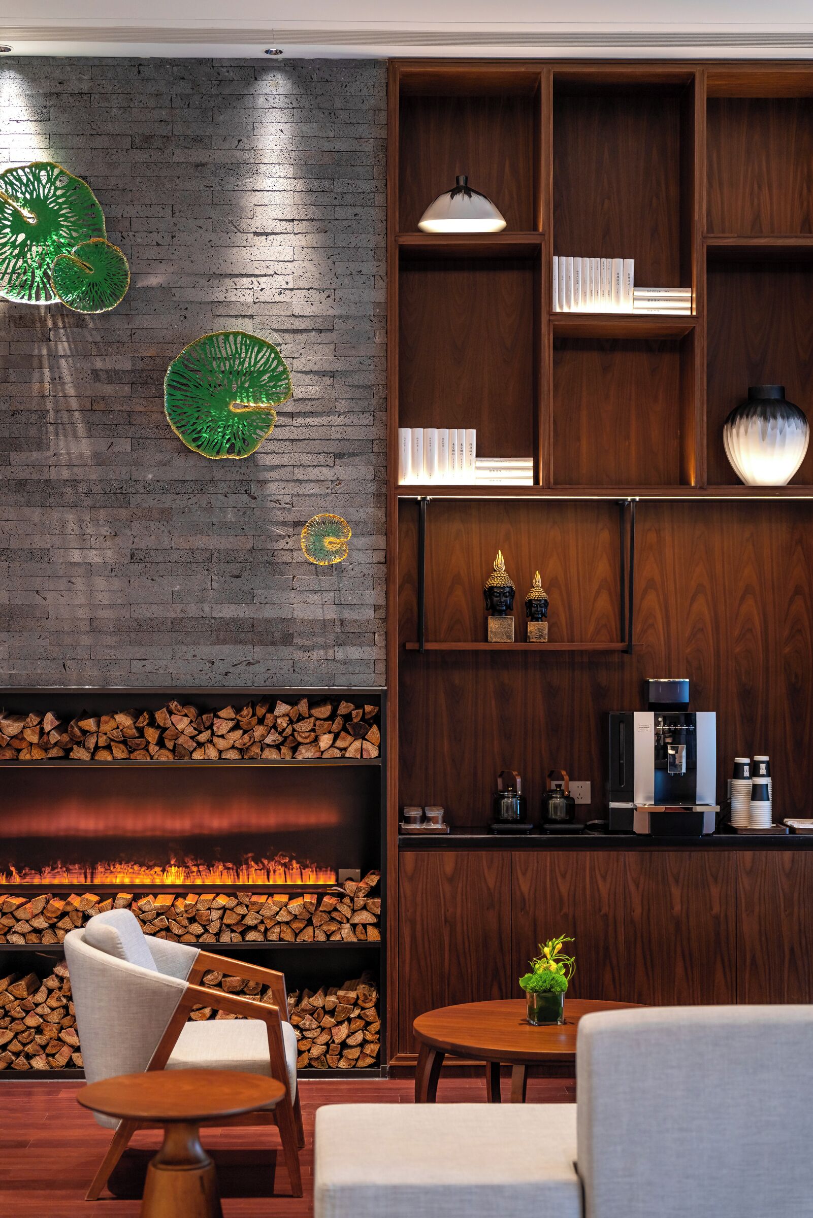 A cozy seating area with a fireplace, wooden shelves with books and decorative items, and a coffee machine.