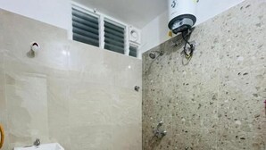 Ein Badezimmer mit Toilette, Waschbecken, Dusche und einem kleinen orangen Eimer.
