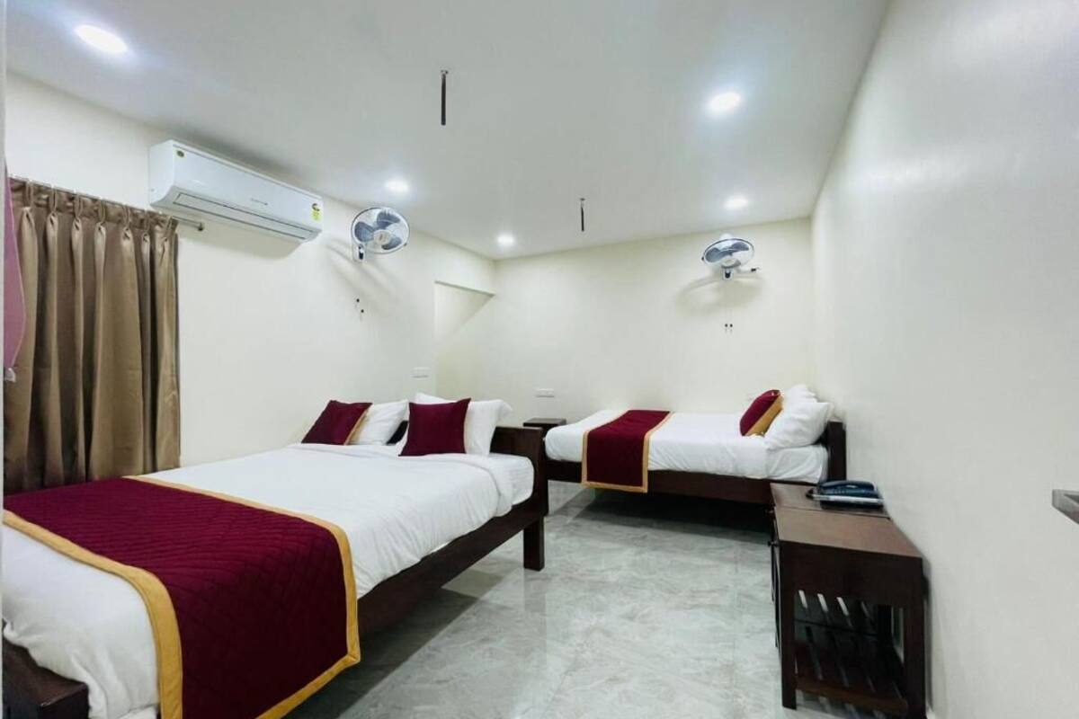 Habitación de hotel con dos camas, un escritorio y un equipo de aire acondicionado.