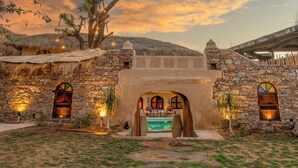 Un edificio de piedra con piscina, rodeado por un muro de piedra y un árbol.