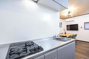 A modern kitchen with a gas stove, a sink, and a dining area with chairs.
