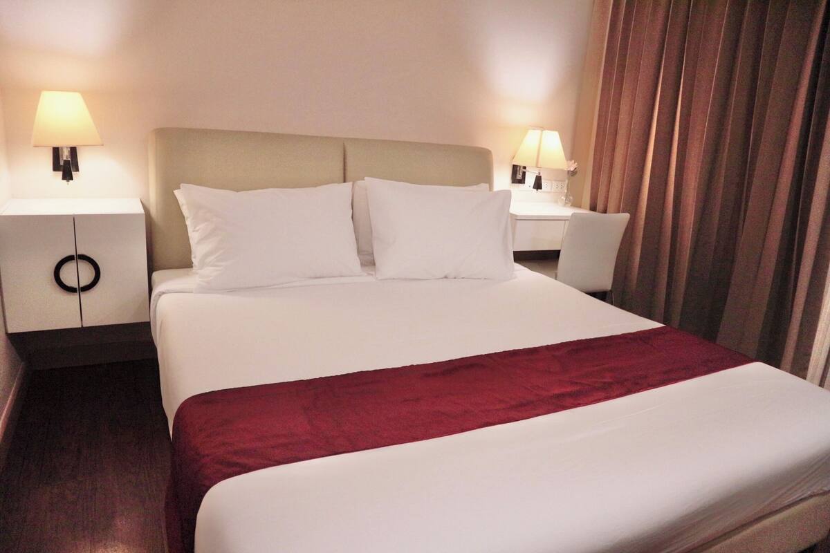 Een hotelkamer met een bed, twee nachtkastjes en een stoel.