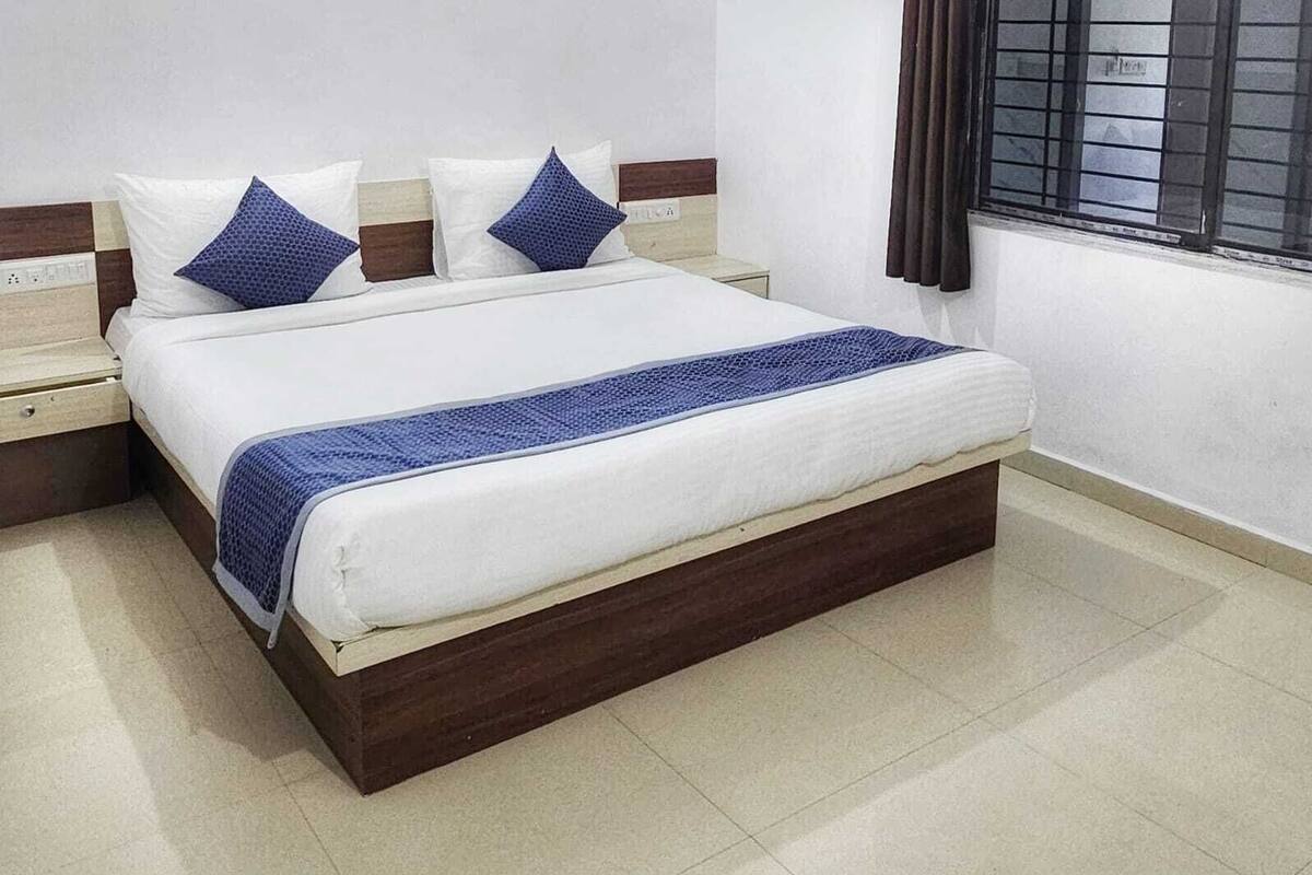 Un lit bien fait, avec une structure en bois, une literie blanche et des touches de bleu.