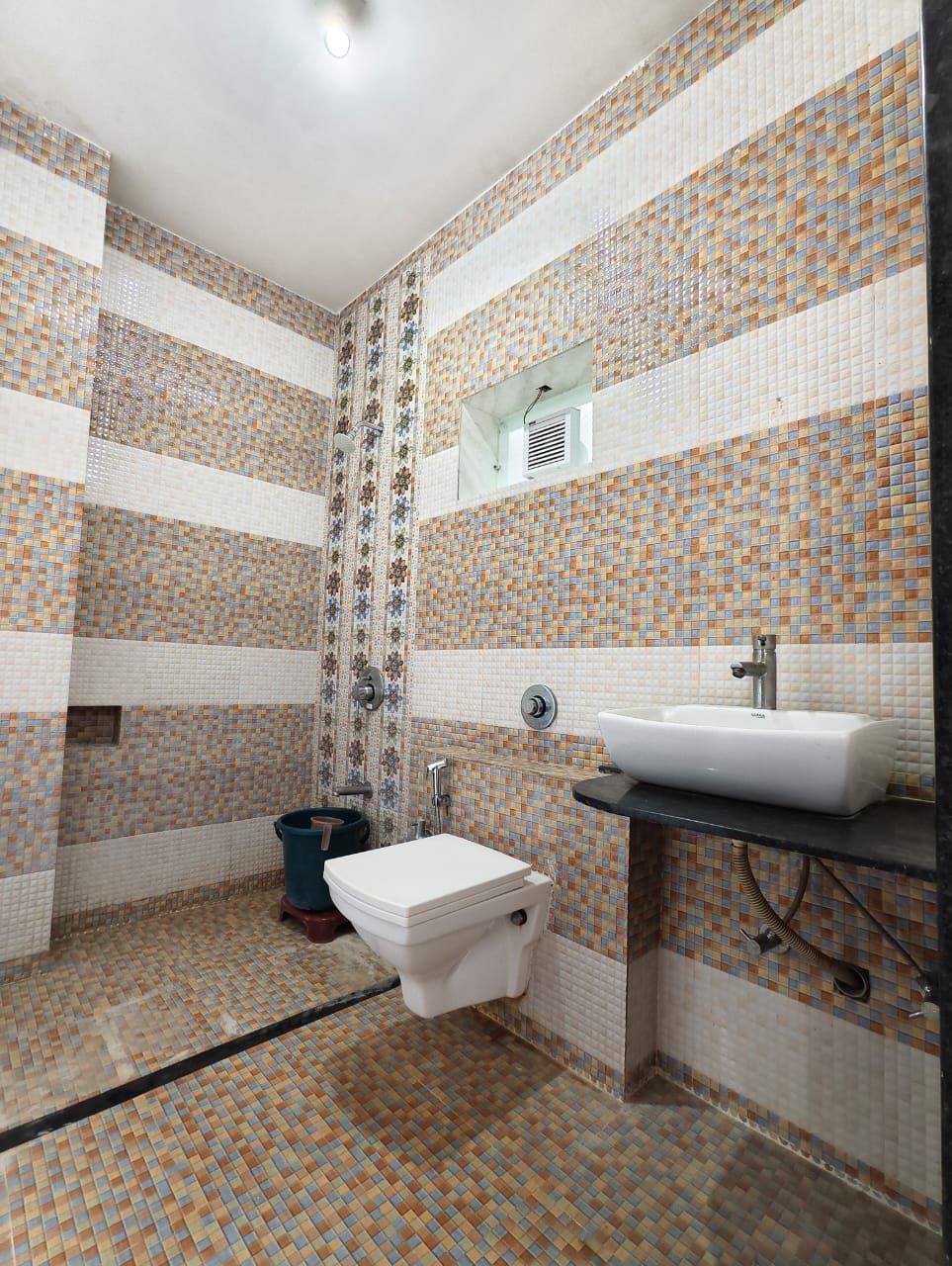 Um banheiro com piso ladrilhado, vaso sanitário, pia e área de chuveiro.