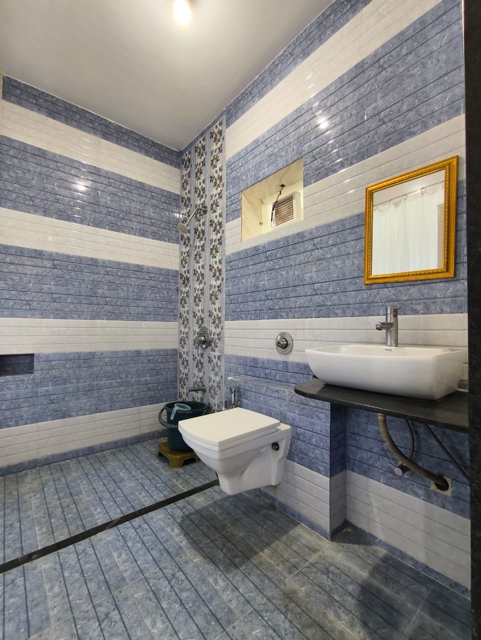 A bathroom with striped tile walls, a toilet, a sink, and a shower.