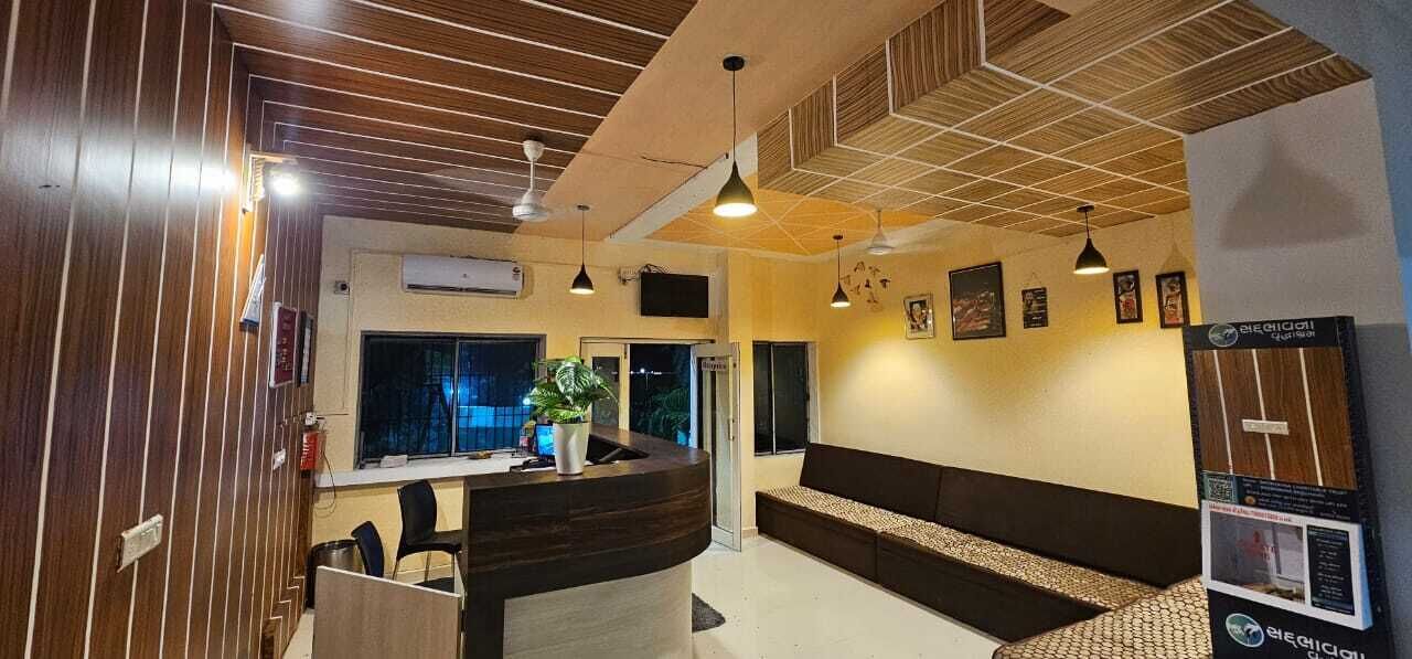 A reception area with a wooden reception desk, a seating area with a sofa, pendant lighting, and a potted plant.
