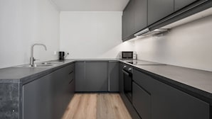 A modern kitchen with dark cabinetry, a stainless steel sink, and a microwave. - Large Single-family Home - Central in Voss (Voss)