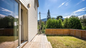 A wooden deck leading to a glass door, surrounded by a fenced yard with a wooden fence and greenery. - Large Single-family Home - Central in Voss (Voss)