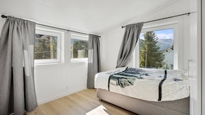 A bedroom with a bed, two windows, and a view of trees and mountains. - Large Single-family Home - Central in Voss (Voss)