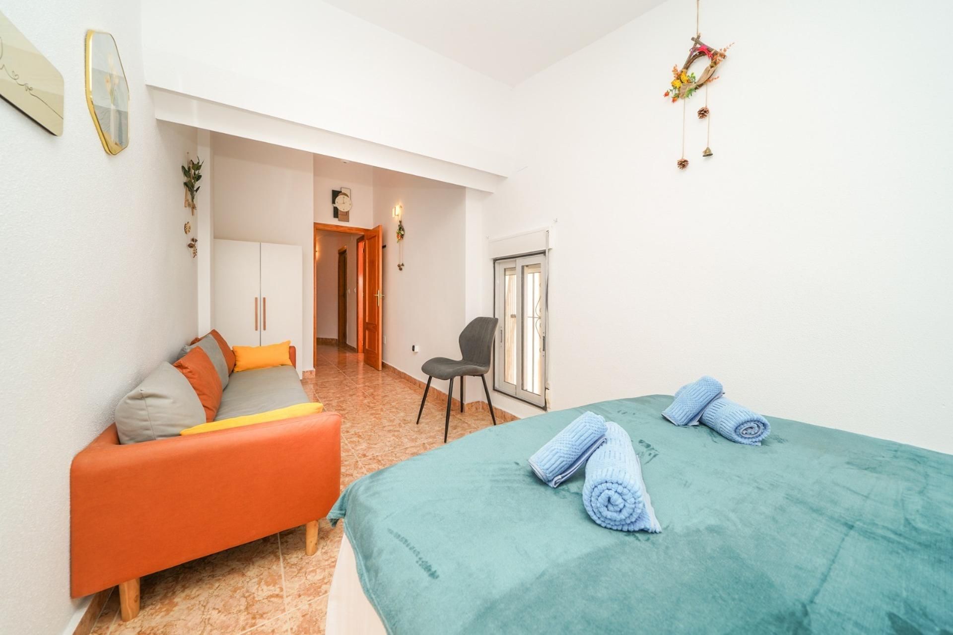 Ein Schlafzimmer mit einem Bett, einem Sessel, einer Couch und einer Tür zu einem anderen Raum.