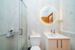 A bathroom with a toilet, a sink, a mirror with a wooden frame, and a glass shower enclosure. - 4-bed Villa, Sleeps 8, Pets Ok & 10 min to Beach (Los Alcazares)
