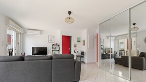 A modern living room with a grey sectional sofa, a flat-screen TV, and a red accent wall.