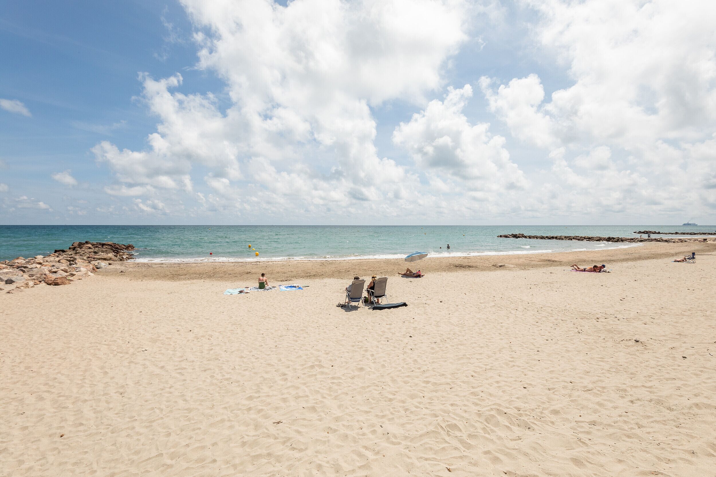 A wide sandy beach with a clear sky and calm sea.