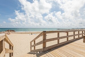 A wooden boardwalk leading to a sandy beach with a clear sky and calm sea. - REVE DE MER, Duplex 6 pers en bord de plage. (Frontignan)
