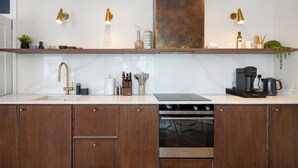 A modern kitchen with a marble countertop, stainless steel appliances, wooden cabinets, and gold fixtures.