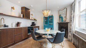 A modern kitchen with a round dining table, black chairs, and a chandelier.