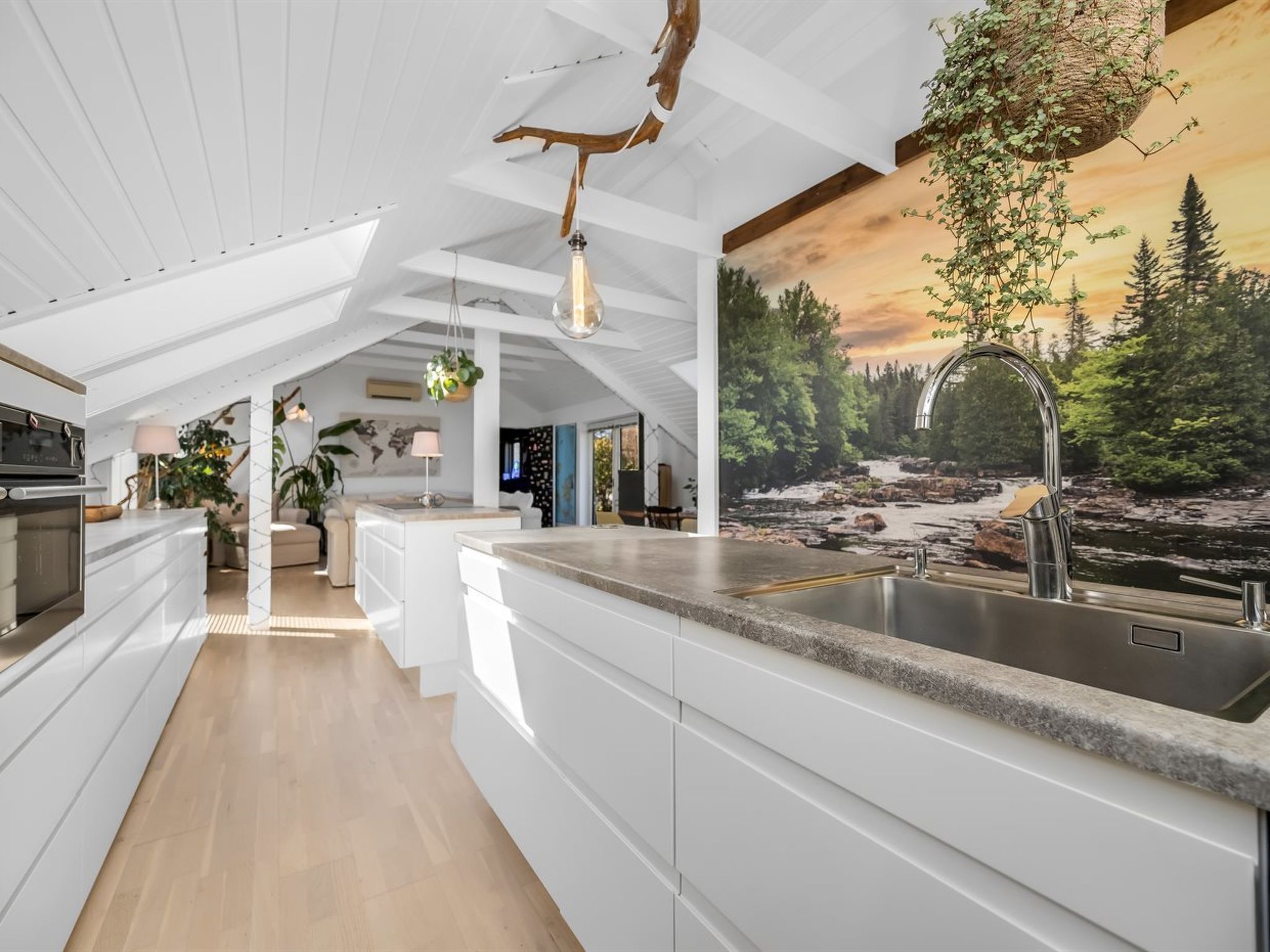 Una cucina moderna con una grande isola, un lampadario e un quadro raffigurante una scena di bosco.