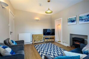 Una sala de estar con sofá, televisión, chimenea y alfombra estampada.